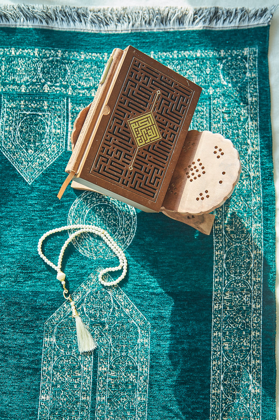 Turquoise Mecca prayer mat styled with a gifted Quran box and tassel