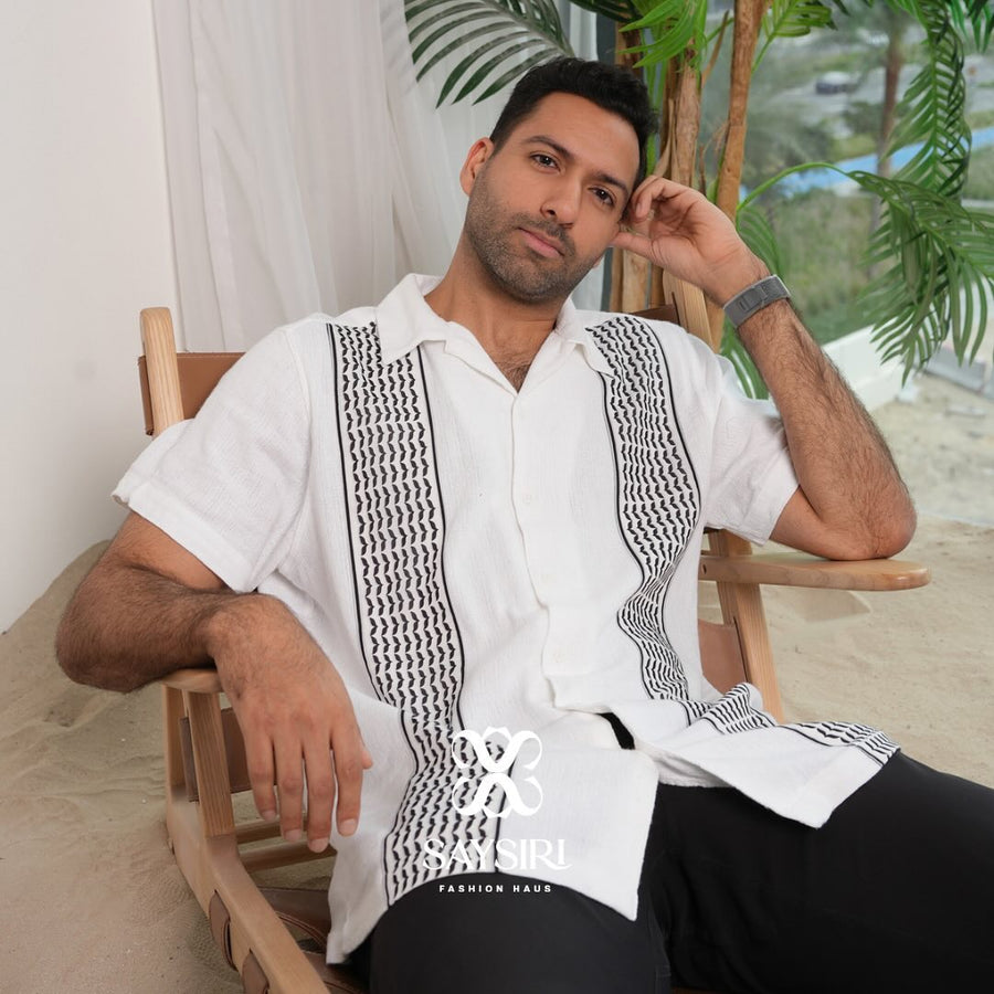 Model seated wearing the Men's Keffiyeh Camp Collar Shirt, relaxed unisex fit