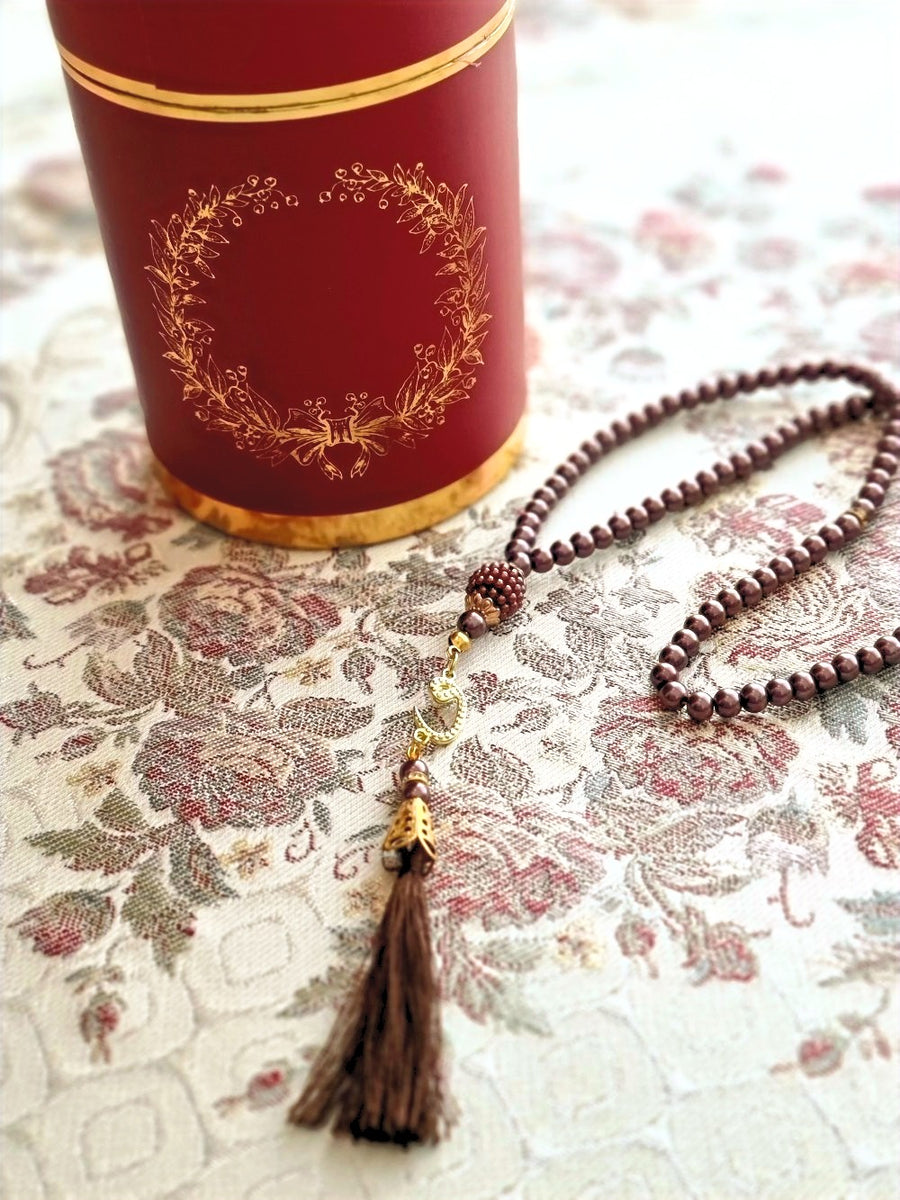 Floral sajadah styled with red canister and brown tasbih — gifting detail