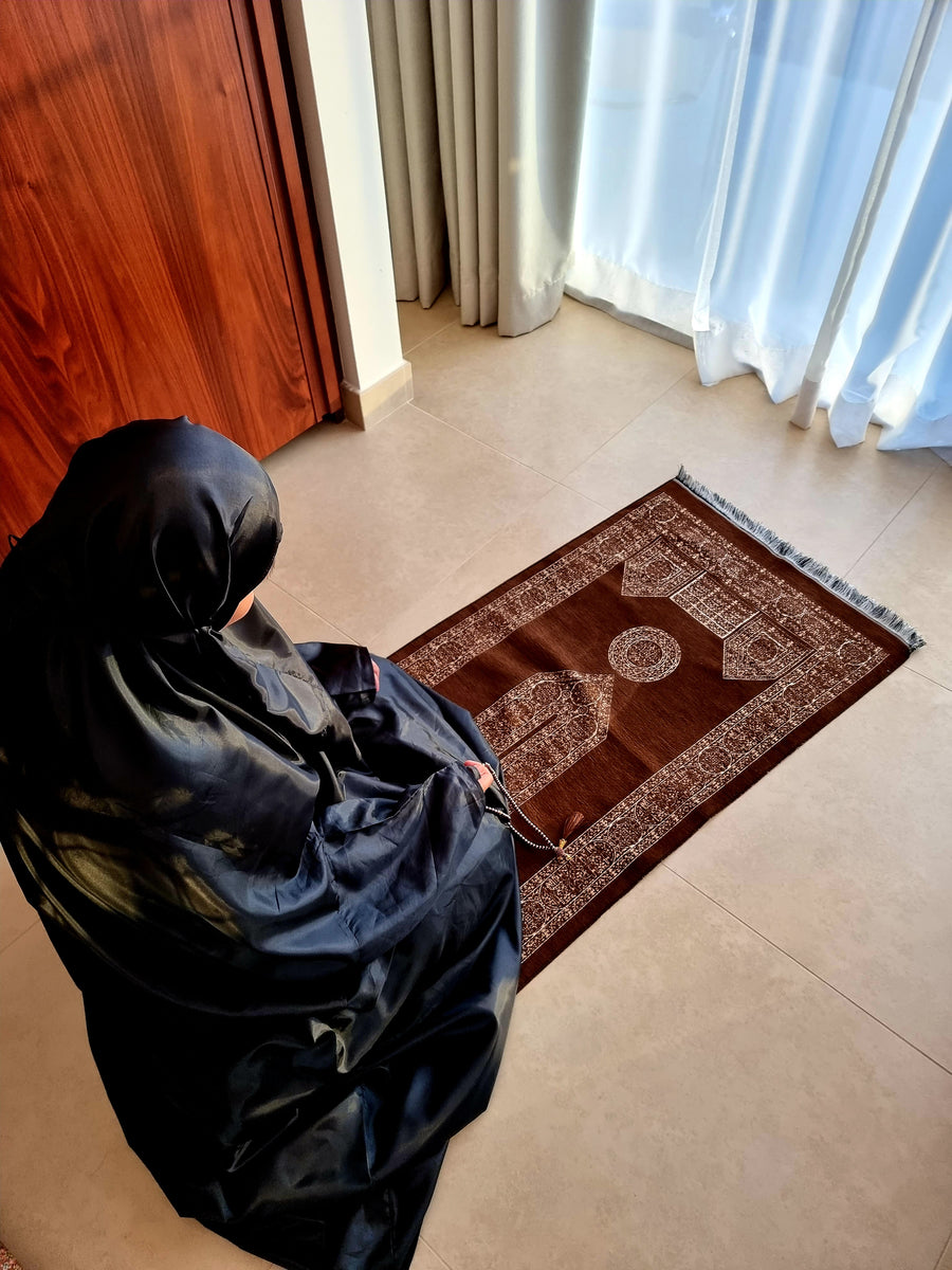Woman praying on the Caramel Earth Mecca Collection sajadah by the window