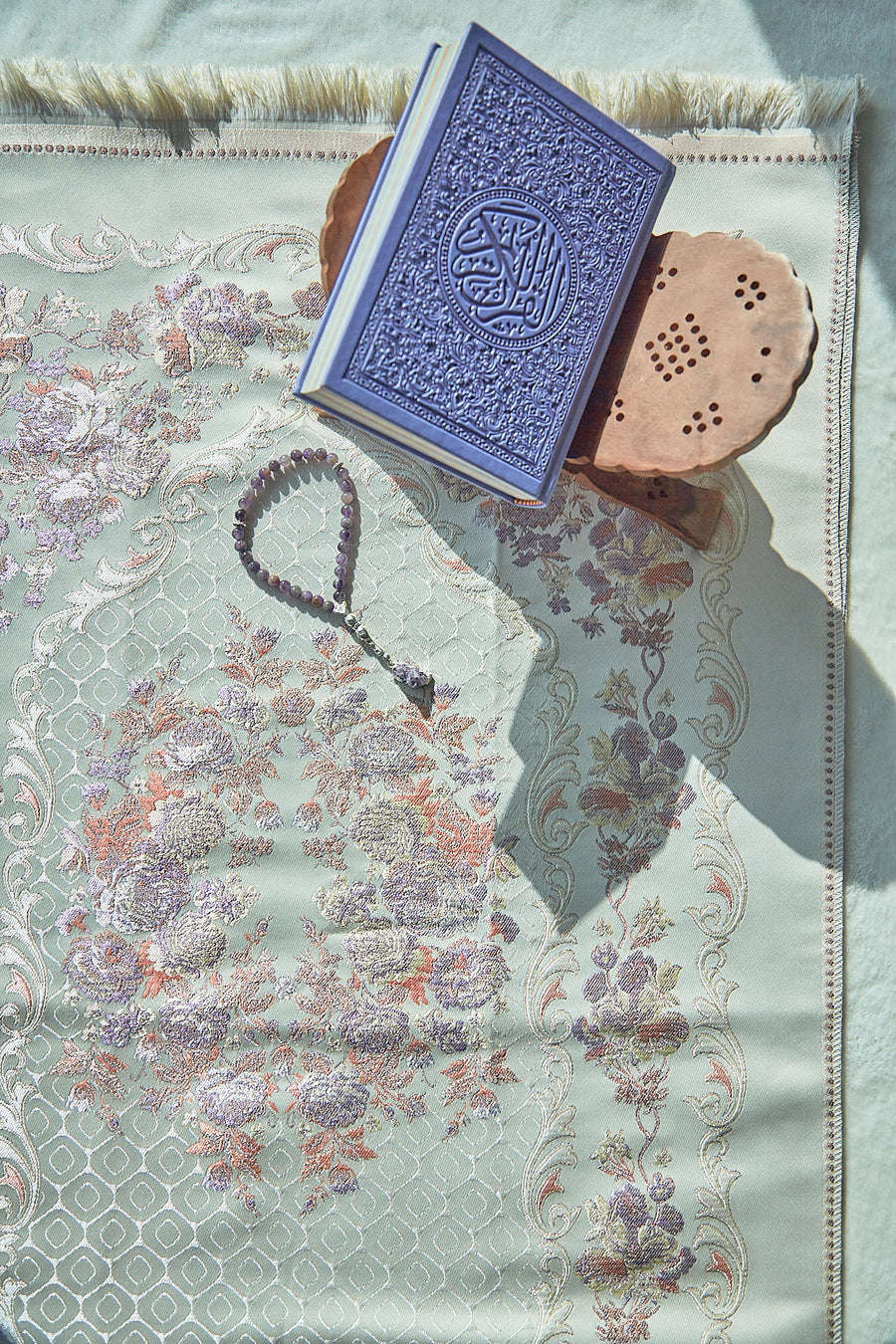 Lavender Safia floral sajadah with Quran and prayer beads, overhead view